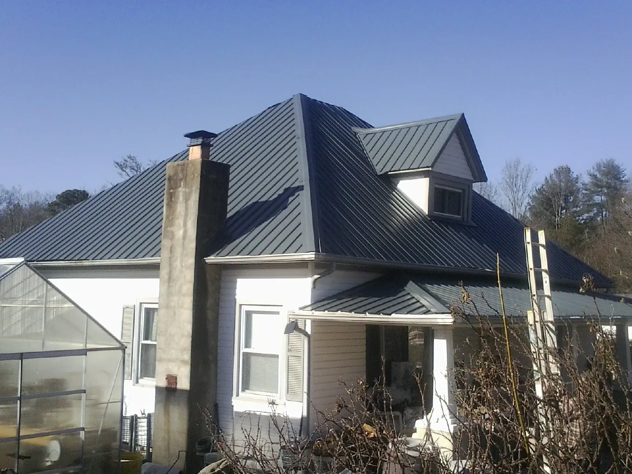 Dark blue standing seam metal roof on a white farmhouse with dormer — Slate & Tile Roof Repair by Roofing Brothers in Parkers Lake