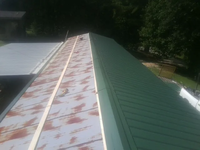 Old rusted panels beside newly installed green metal roofing — Wind Damage Roof Repair by Roofing Brothers in Parkers Lake