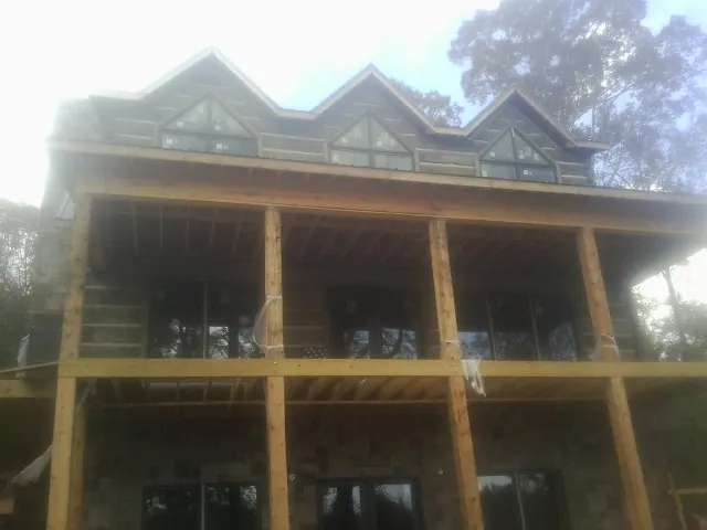 Dormers and porch framing on a large log home under construction — Roof Coating work by our crew in Parkers Lake