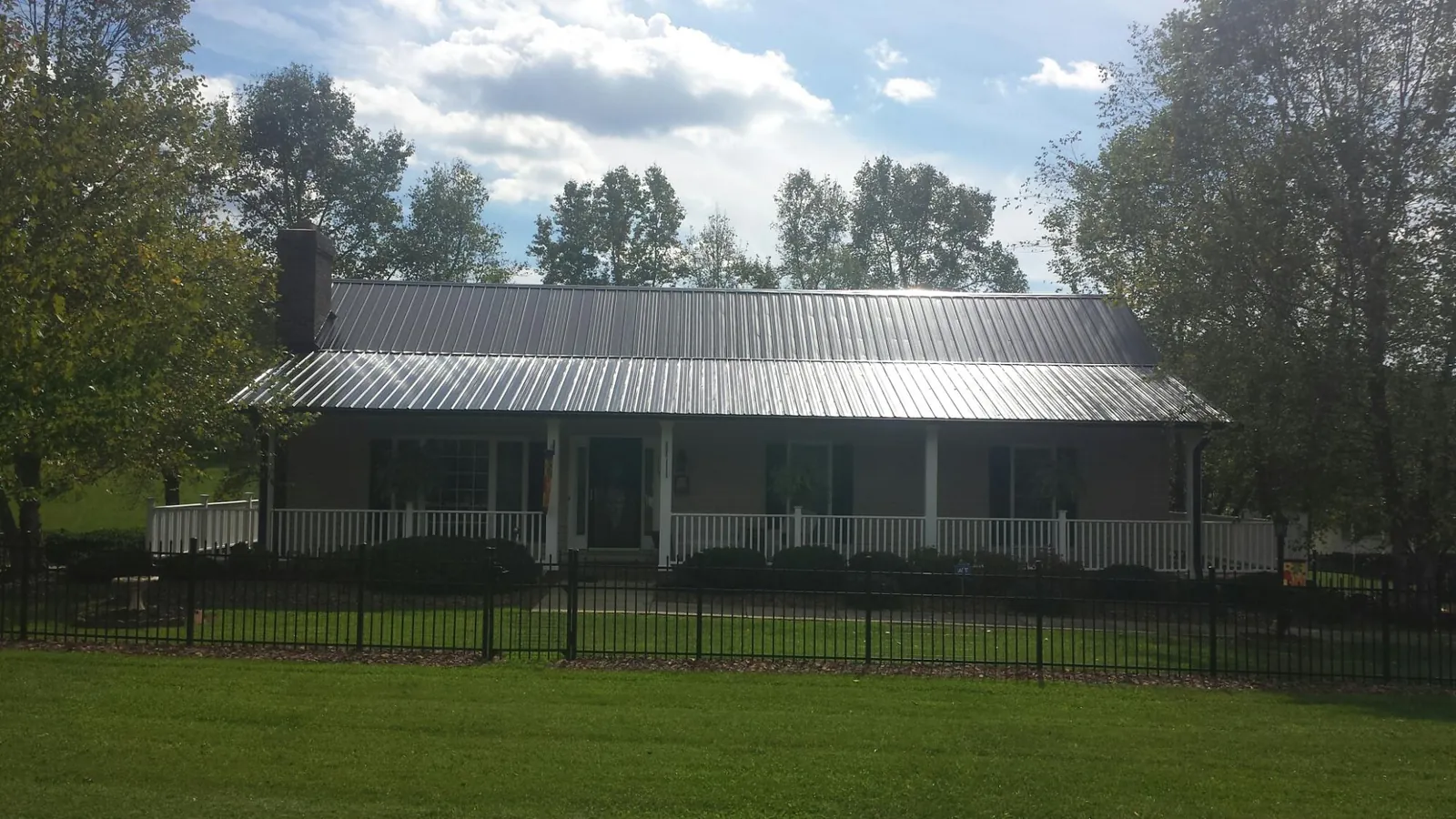 Gray metal roof on a brick ranch with a full width front porch — Gutter Guard Installation work by our crew in Parkers Lake