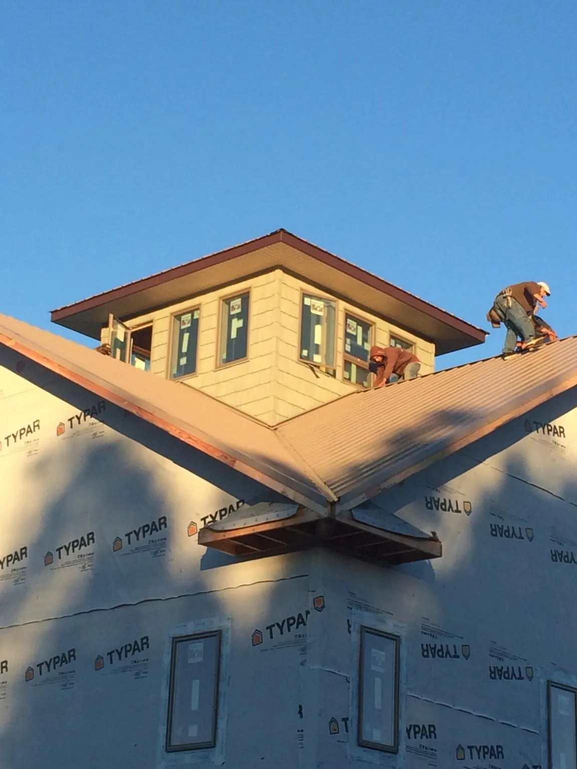 Roofers working around a rooftop cupola on a new metal roof at sunset — Roof Waterproofing in Parkers Lake by Roofing Brothers